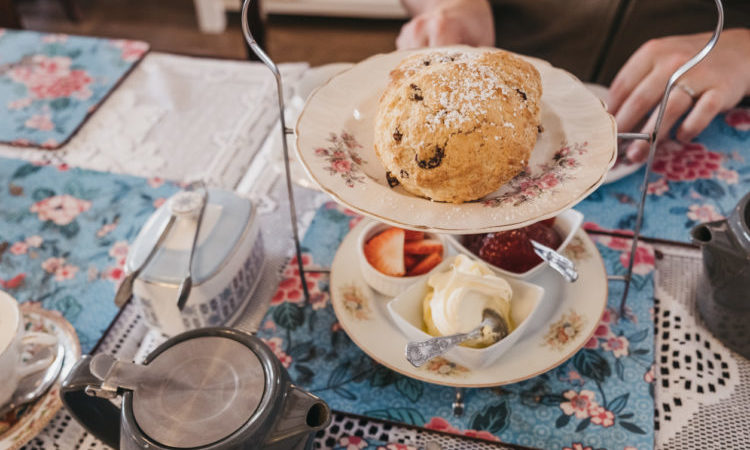 View from above of fruit scones, jam and cream, known as afternoon tea in UK, served on a vintage trays and setting on a table, selective focus.