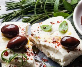 Feta cheese with olives and green herbs on gray marble background